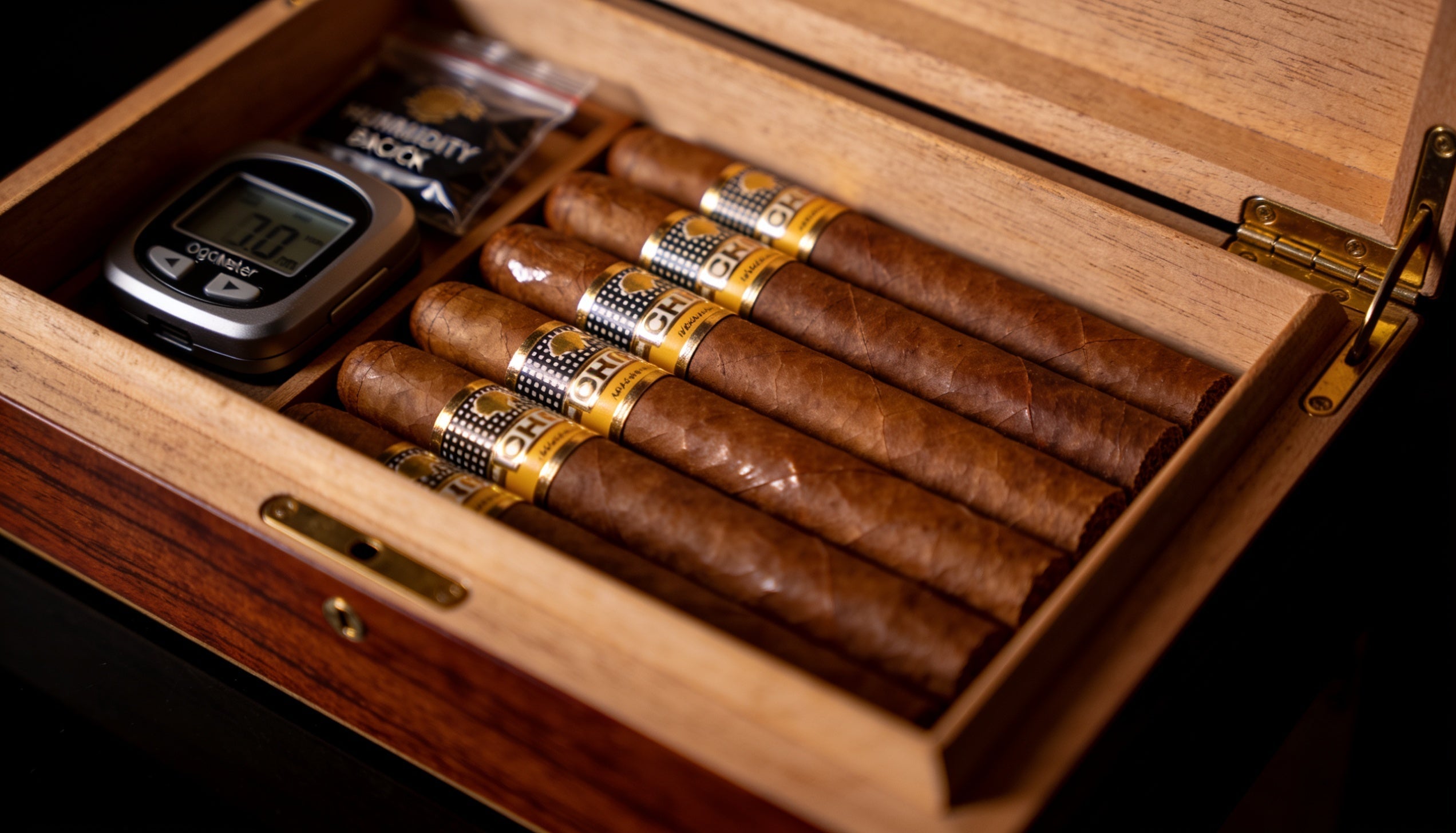 Premium cigars aging inside an open wooden humidor with a humidity pack, showing how to age cigars